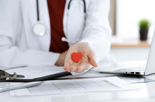 Un médico muestra en su palma la figura de un pequeño corazón