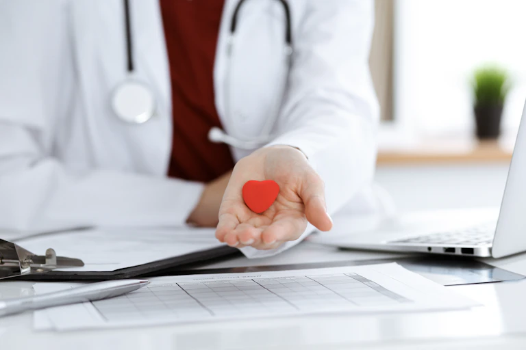 Un médico muestra en su palma la figura de un pequeño corazón