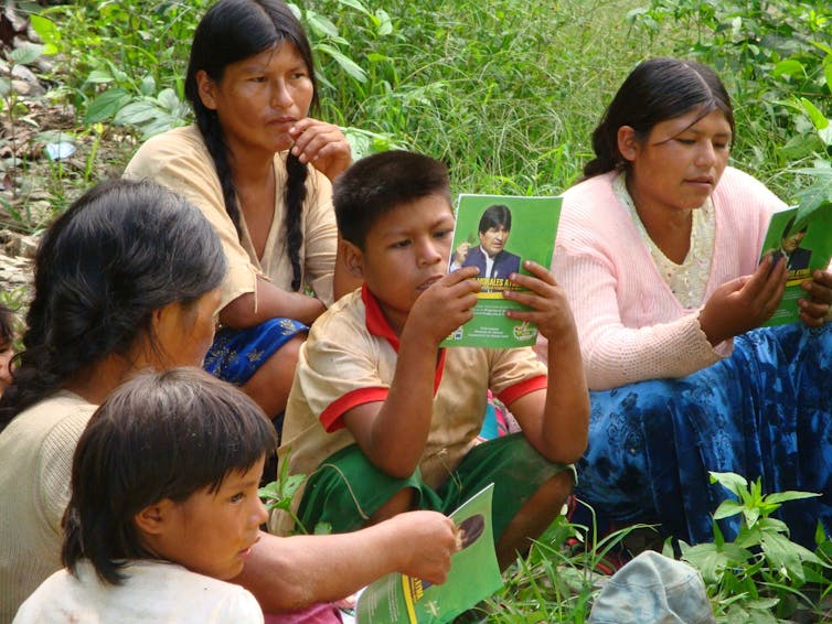 Three women and two children read green leaflets.