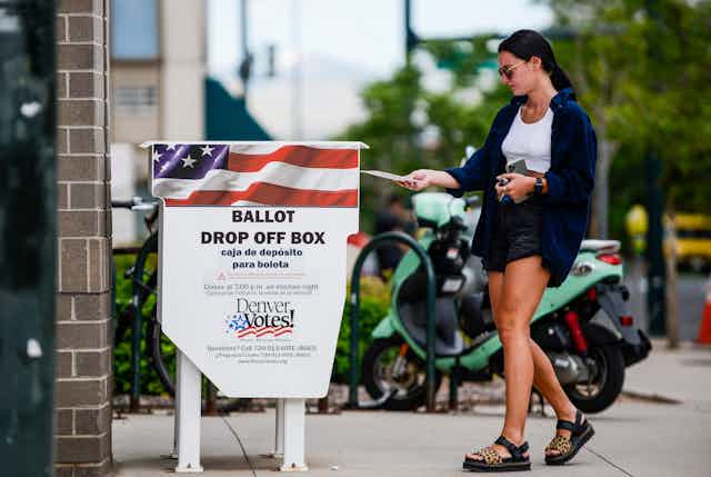 A woman dropping off a ballot in a drop-off box in Denver.