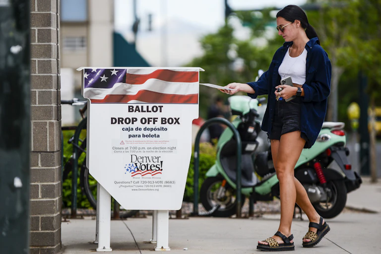 A woman dropping off a ballot in a drop-off box in Denver.