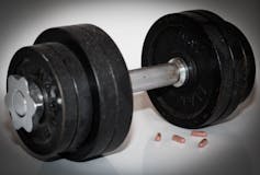 A black dumbbell with drug capsules in the foreground