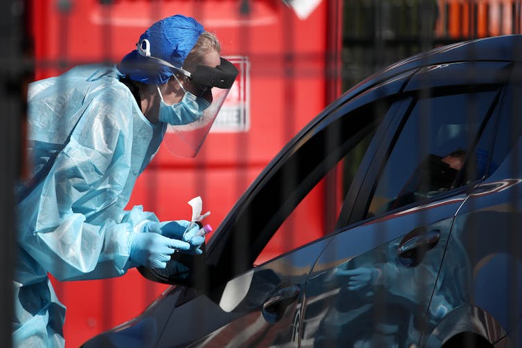 Nurse in protective clothing testing car
passenger