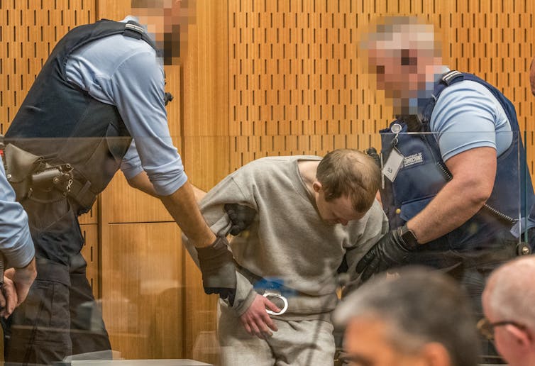 man in handcuffs held by two police officers