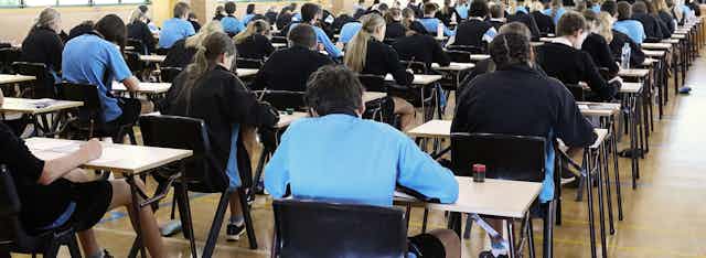 Backs of students in an exam hall taking a test.