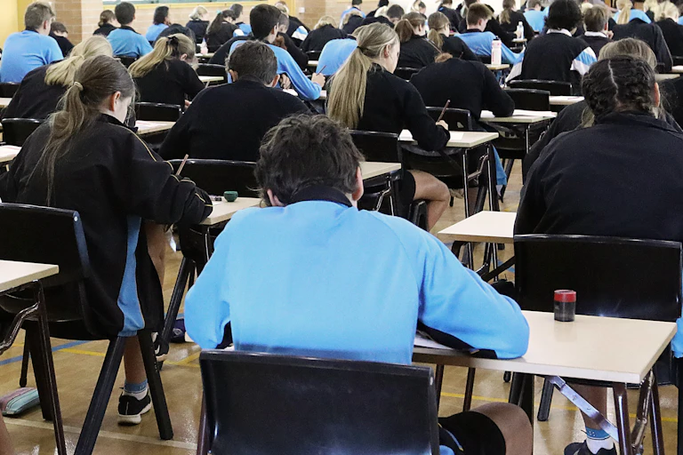 Backs of students in an exam hall taking a test.
