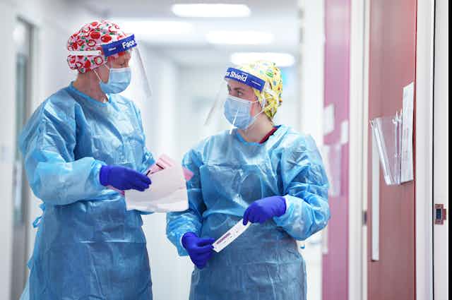 Two nurses wearing personal protective equipment including face shields
