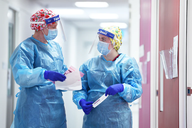 Two nurses wearing personal protective equipment including face shields
