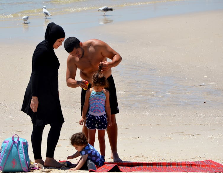 Muslim family putting on blockout at the beach