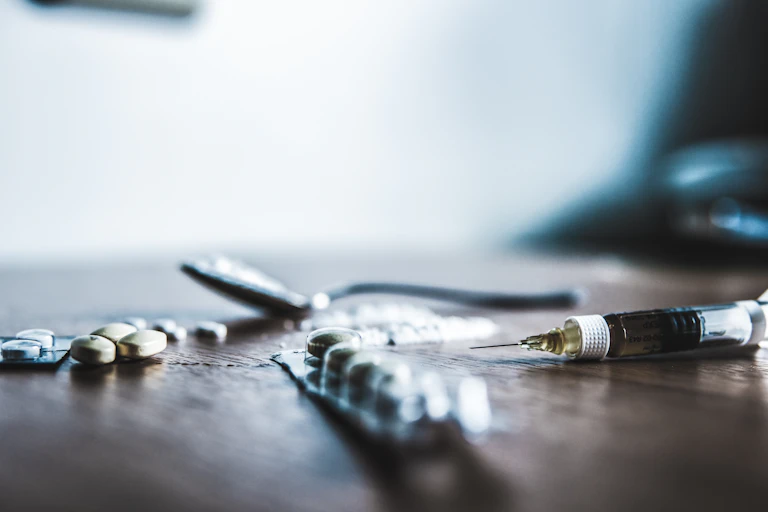 Drugs on table including tablets, a syringe, and a powder.