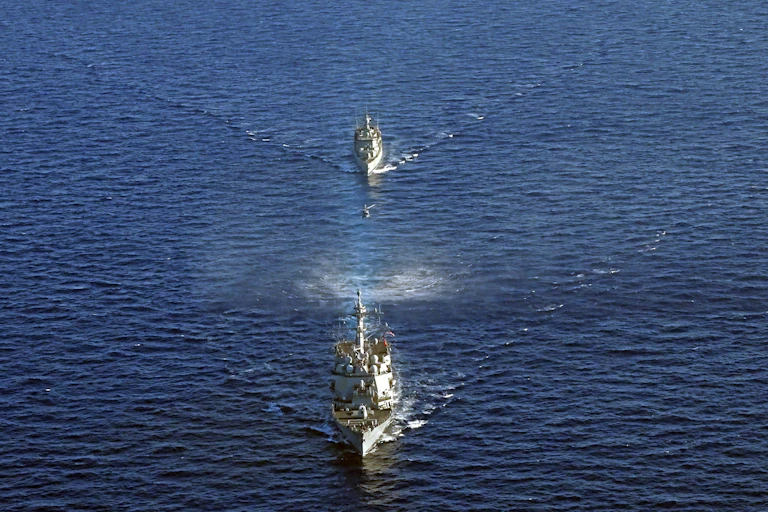 Military ships sail through waters around Crete.