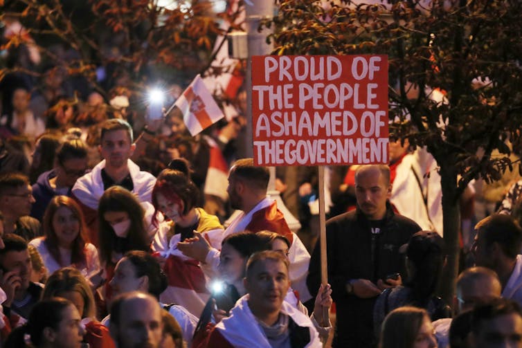 Belarus protestors hold sign saying 'Proud of the people, ashamed of the government'.