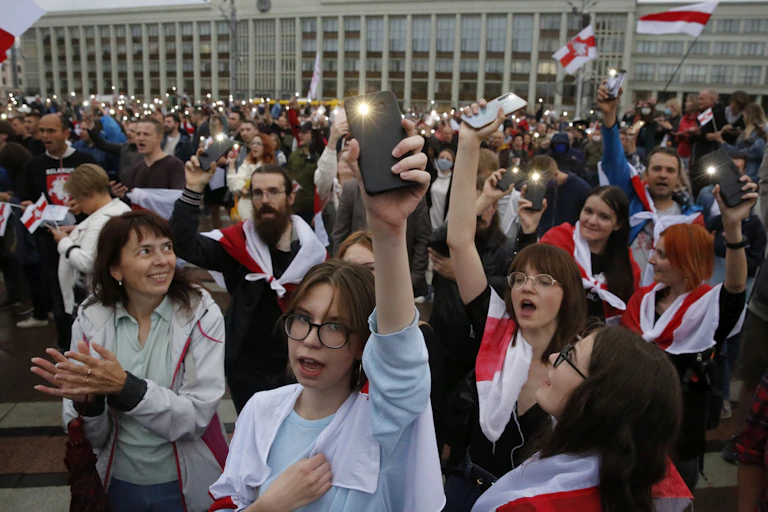 Crowd of protestors in Belarus with flags wrapped around them.