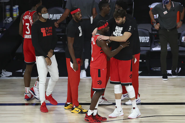 Toronto Raptors guard Terence Davis (0) reacts with center Marc Gasol (33) and other players convene at the side of the court.