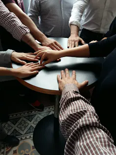 Hands join on a table top.