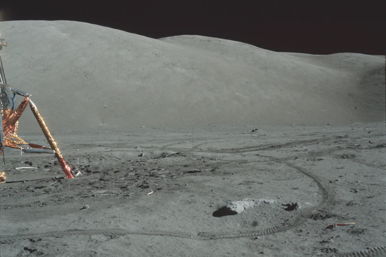 A golden lunar lander and tyre tracks on the Moon.