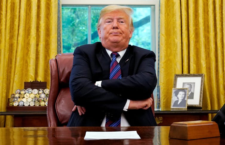 US President Donald Trump sitting at desk in White House