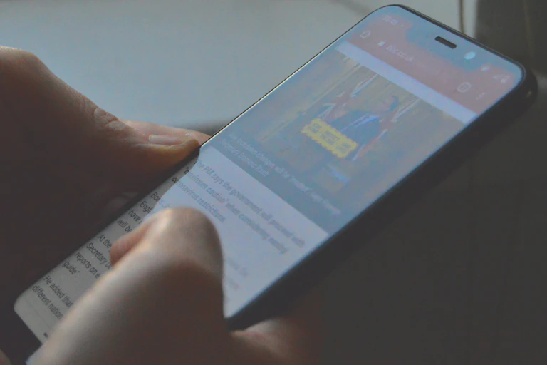 Hands scrolling a news article on a phone
