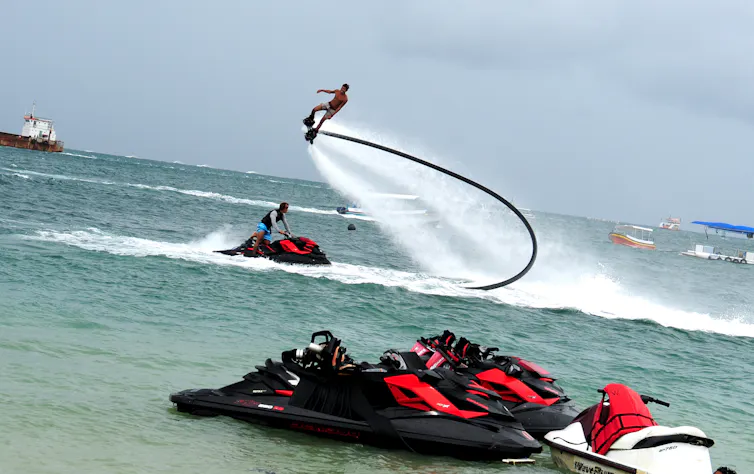 Seorang pemandu wisata memperagakan atraksi gerakan salto dengan 'flyboard' di kawasan pantai wisata bahari Tanjung Benoa, Bali.