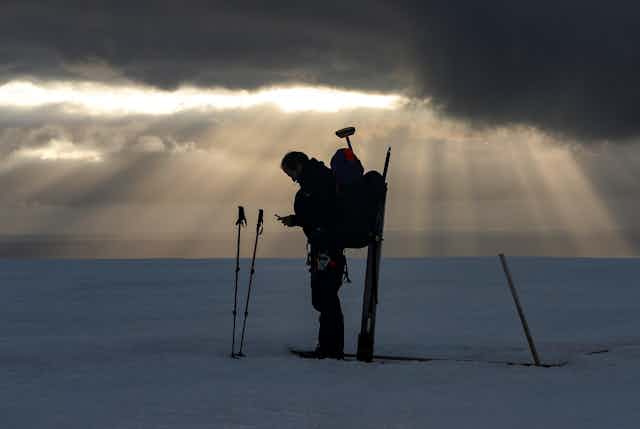 A scientist stands in the middle of a glacier.