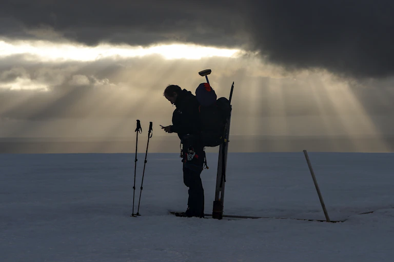 A scientist stands in the middle of a glacier.