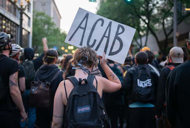 Female protester holds sign with letters 'ACAB'