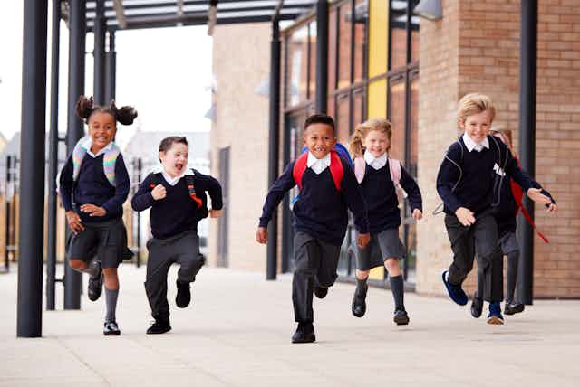 Children in uniform running outside school