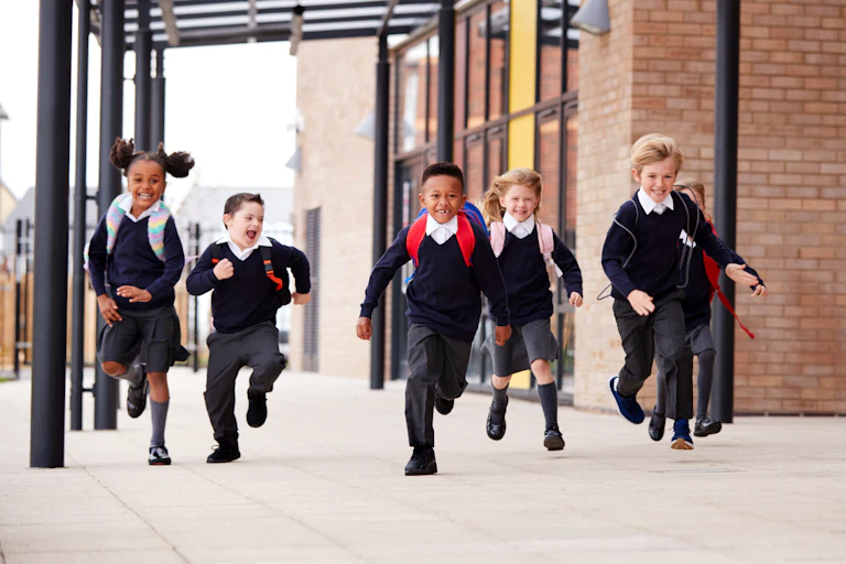 Children in uniform running outside school