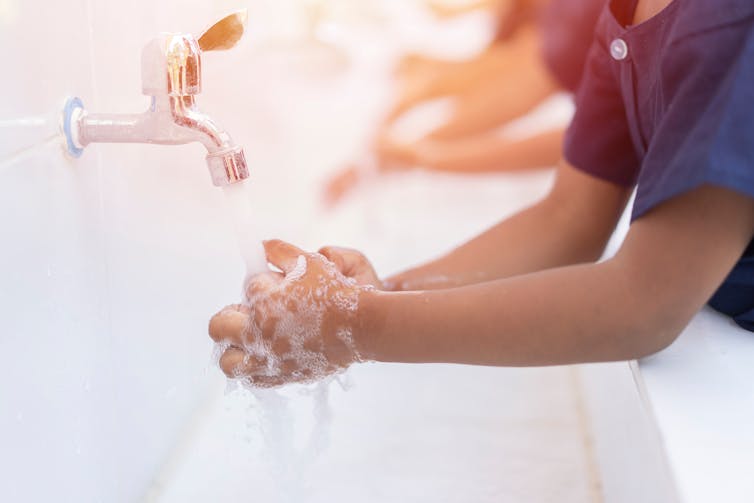 Child washing hands under a tap