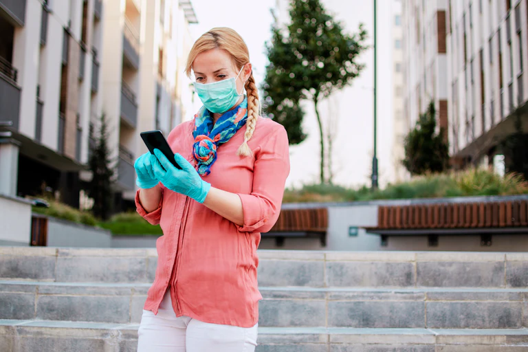 Woman wearing face mask and gloves looking at phone