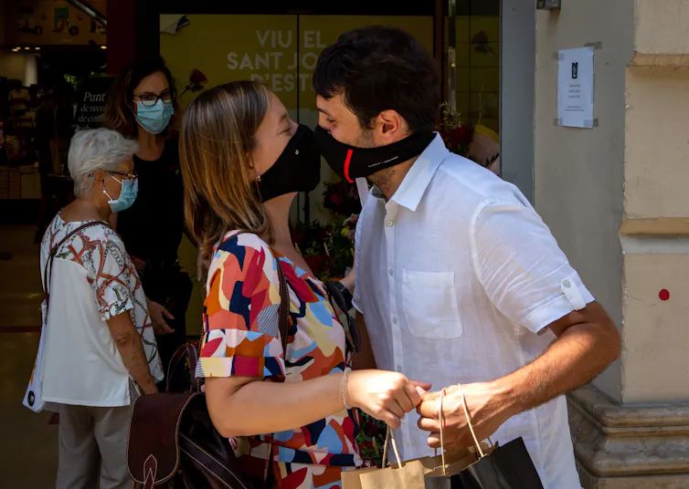Una pareja con máscarillas se besa en Barcelona.