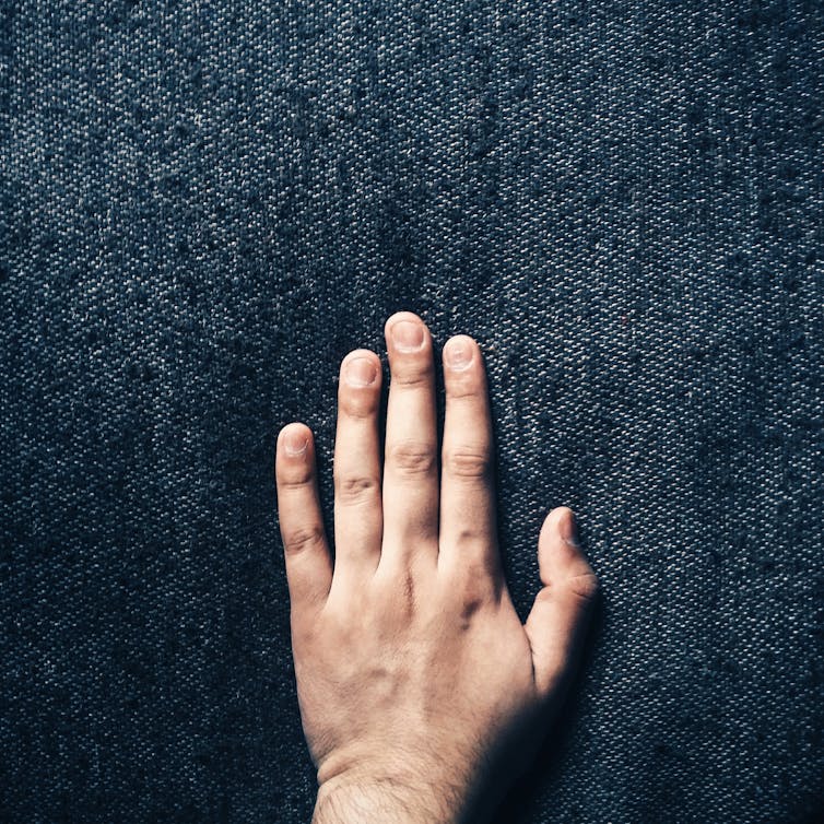 Una mano tocando una tela azul oscuro.