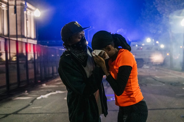 A man helping a woman during a street protest in Kenosha, Wisconsin.