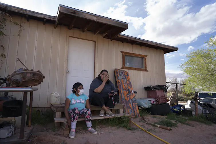 A mother and daughter sit outside their home on the Navajo Nation reservation.