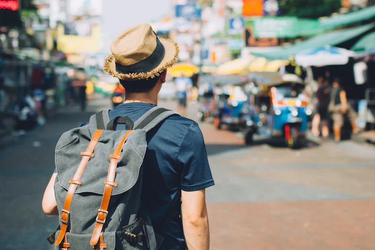 Young man wearing backpack with Asian street in background.
