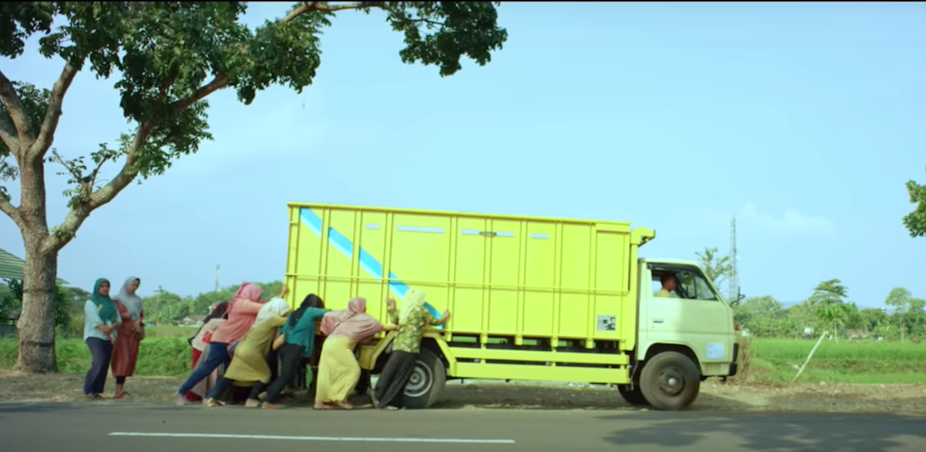 Women pushing a truck on the side of the road in in the film _Tilik_.