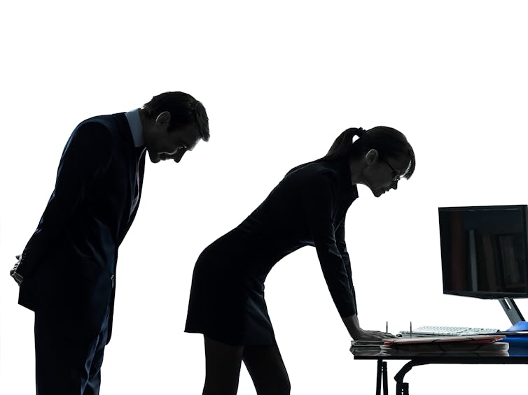 Businessman looking at female colleague's buttocks.