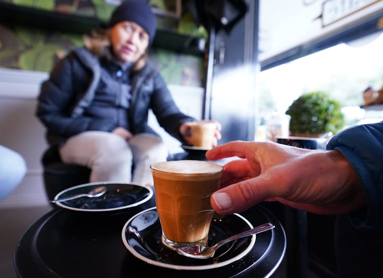 Hand reaching for a coffee in a cafe