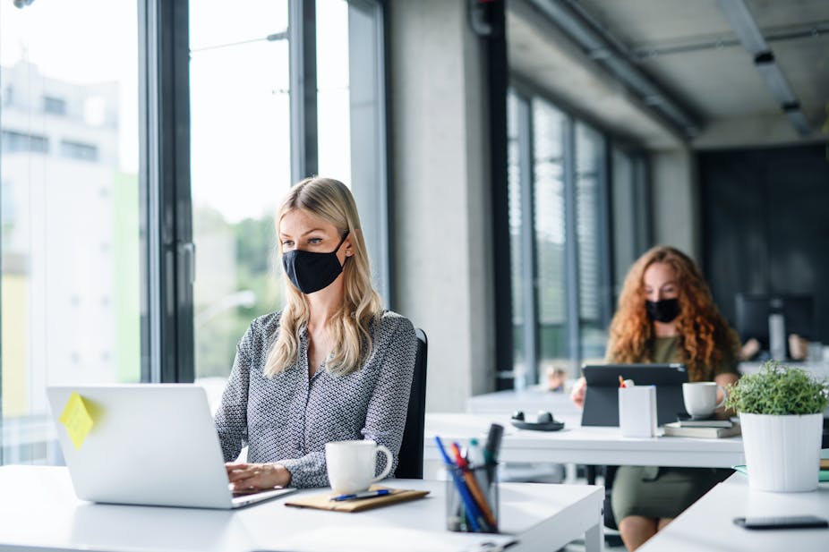 Office workers wearing face masks and sat apart.