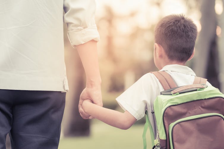 Little boy holding hands with father.