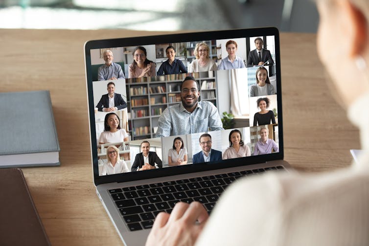 Back view of woman on video call with lots of people.