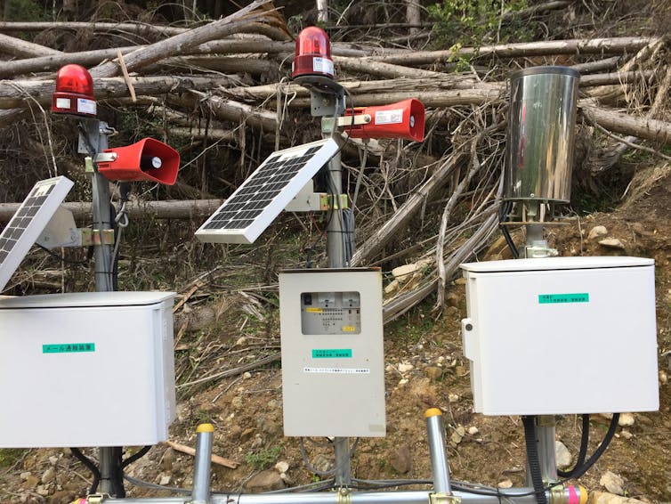 Solar powered rain gauges attached to red loudspeakers.