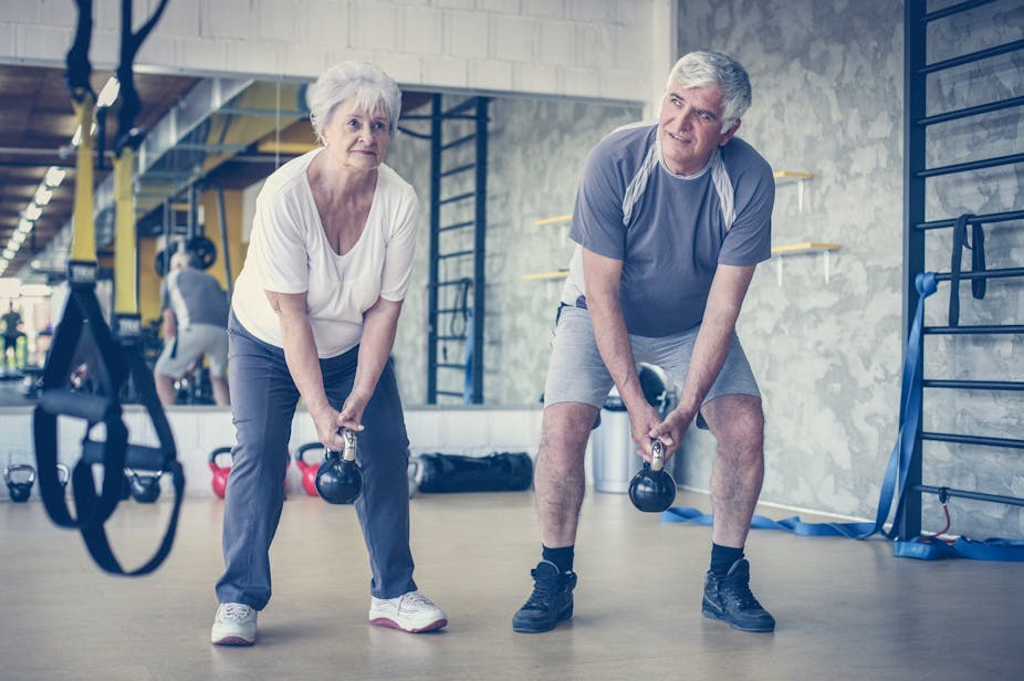 Older couple lifting kettlebells at the gym.