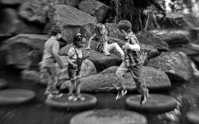 Black-and-white photo of children splashing in rocks.