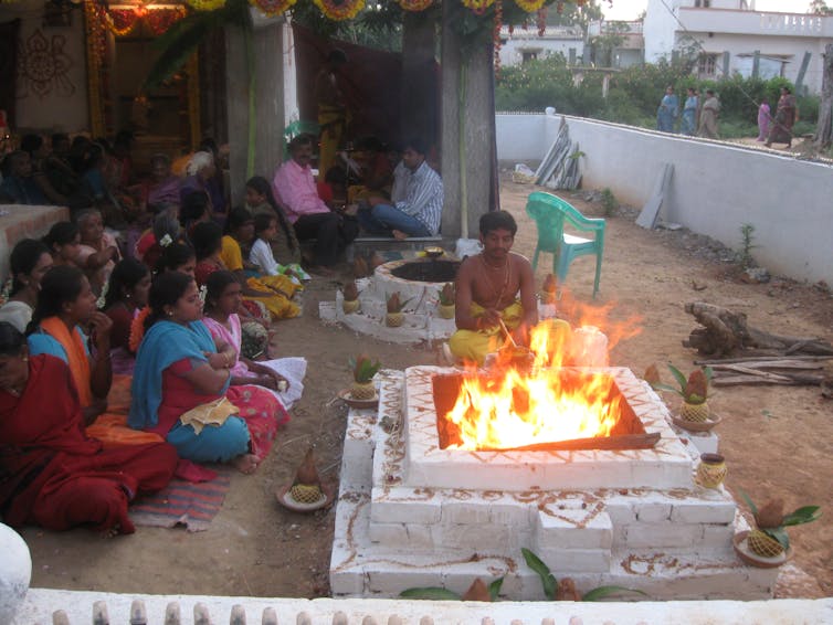 A man sits at a fire altar