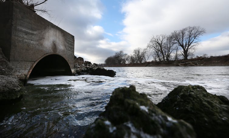 water flows into a river from a pipe connected to a treatment plant