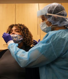 medical worker points swab toward patient's nostril