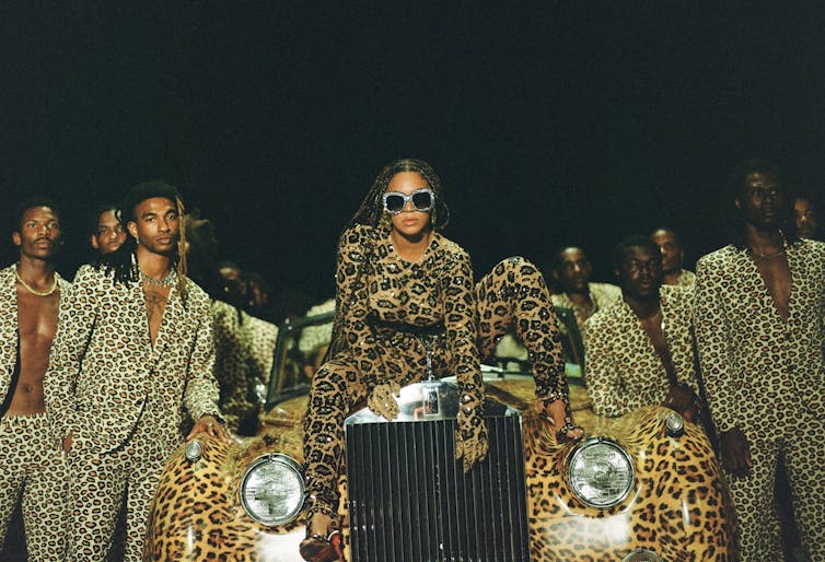 Singer Beyonce in leopard print on car with suited men