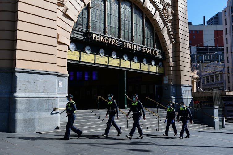 Police officers walking past an empty Flinders Street Station