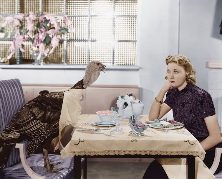 A woman having dinner with a turkey.